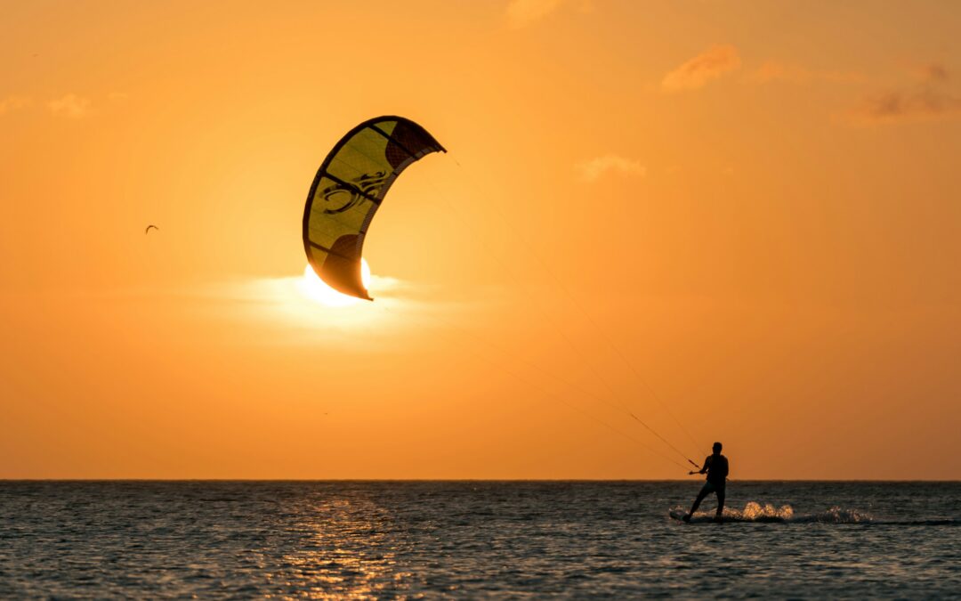 Image depicts a kite surfer on calm waters at sunset in Sicily